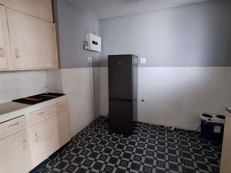 A functional kitchen space featuring built-in cabinetry, tiled splashbacks, and tiled flooring, offering potential for modernization and cosmetic updates.