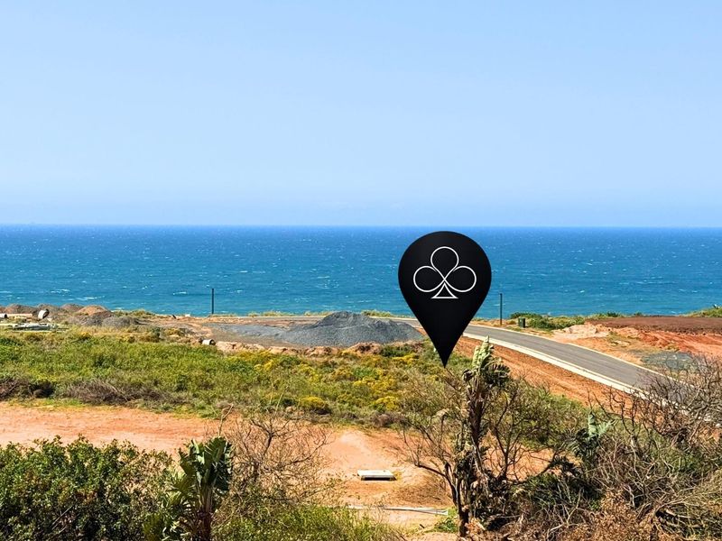 A scenic view of the coastline overlooking vacant residential land with an established paved road and natural vegetation.