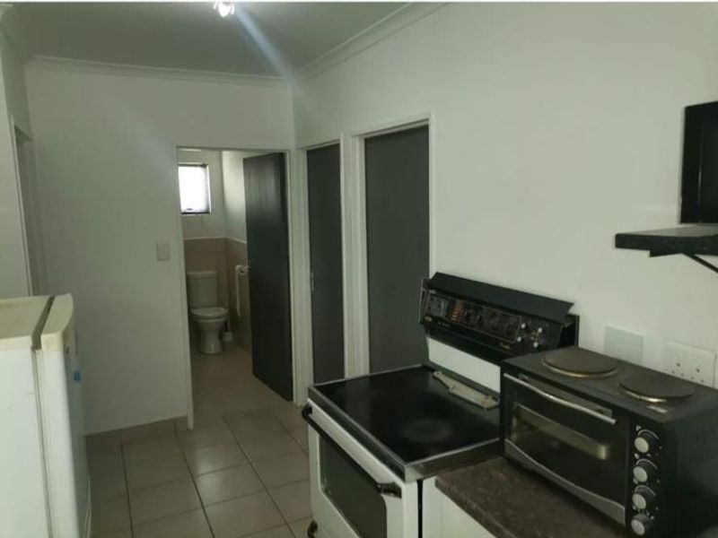 A functional kitchen area featuring tiled flooring and a freestanding stove, with direct access to an adjacent bathroom.