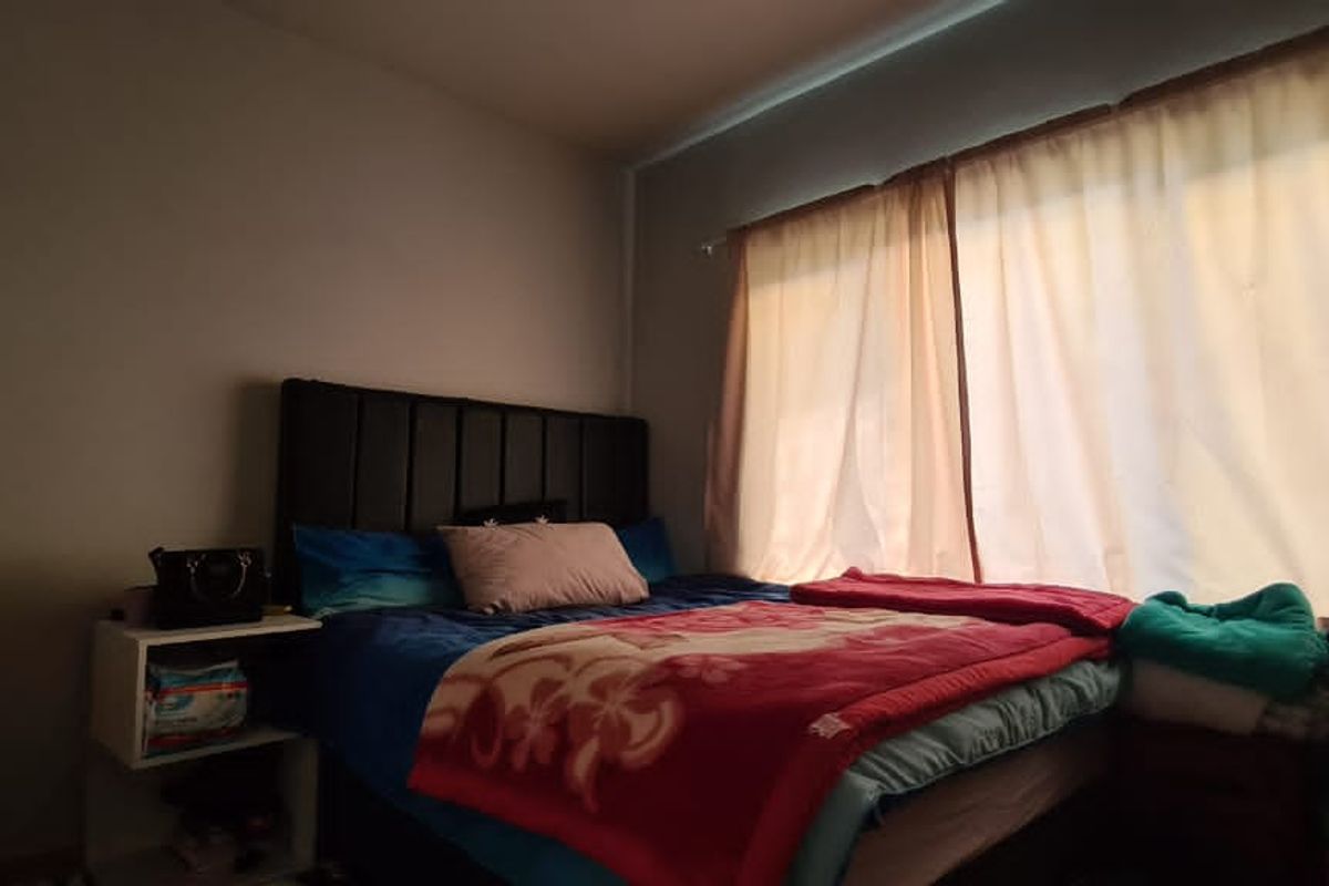 A standard bedroom featuring a window with installed curtain rails, providing natural light to the space.