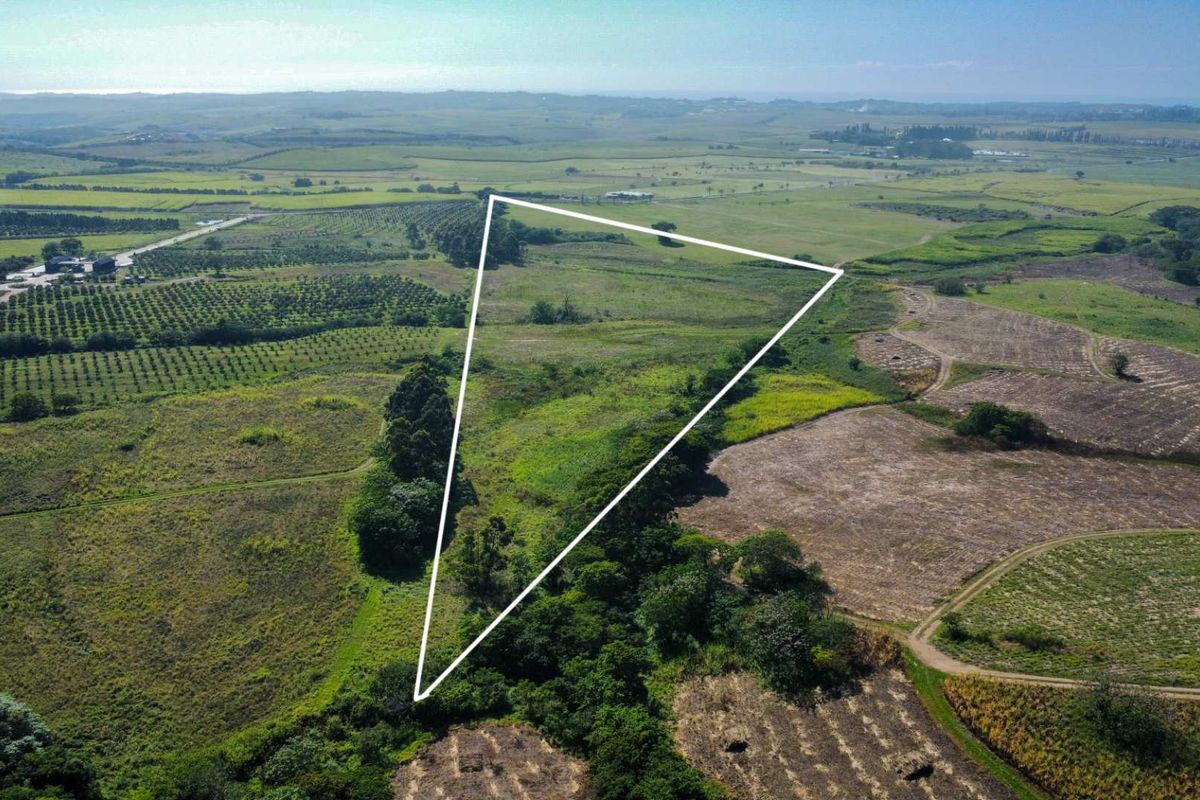 An aerial view of a large, open agricultural farm plot with a white boundary outline highlighting the property's extent.