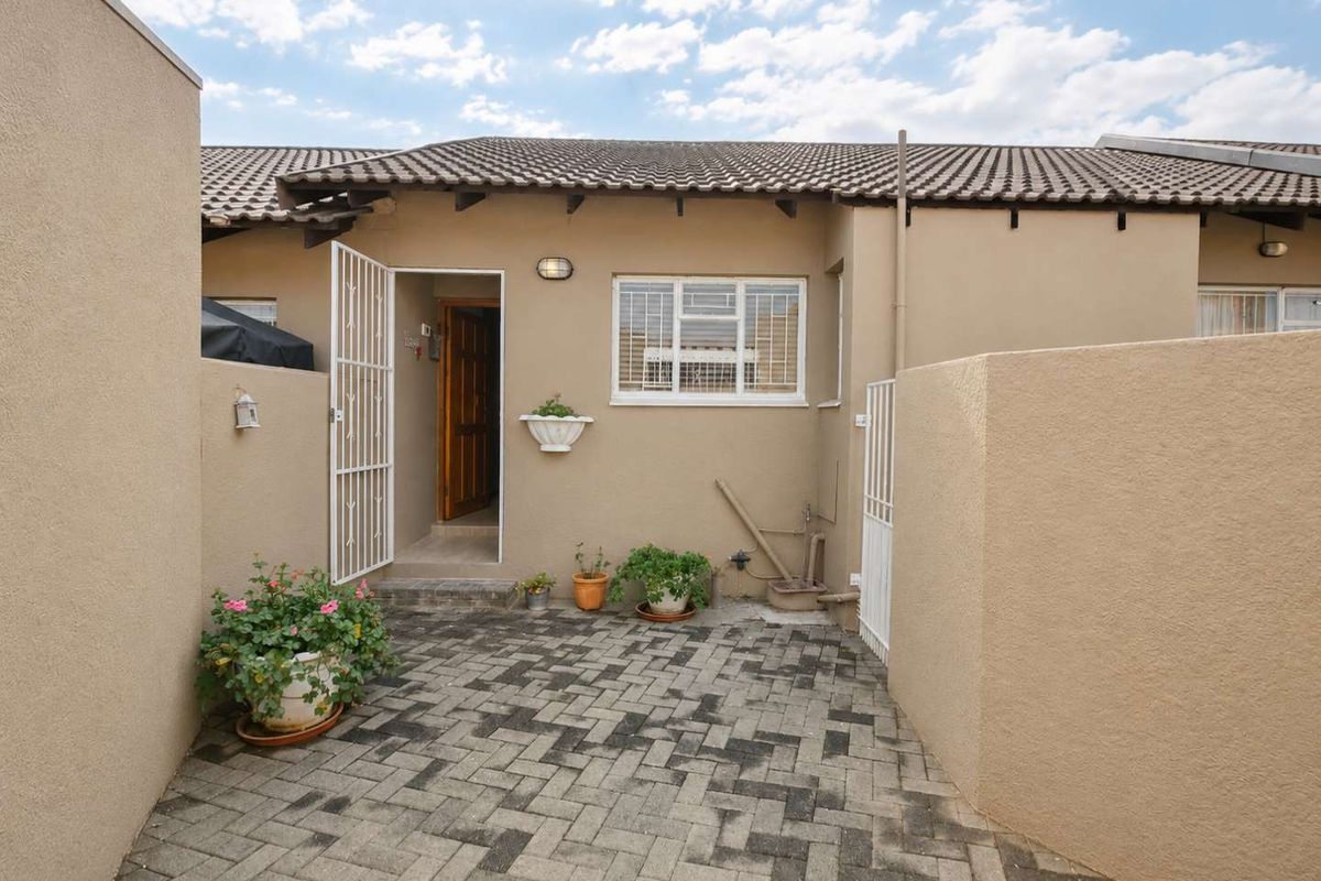 A private rear courtyard featuring paved flooring, a security gate, and a tiled roof overhang, providing a functional outdoor space.