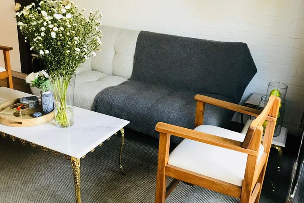 A cozy living room area featuring a white painted brick wall and integrated overhead shelving.