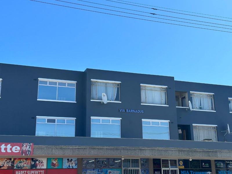 Front elevation of the Via Barnadus building featuring retail storefronts on the ground level and residential apartment windows above.