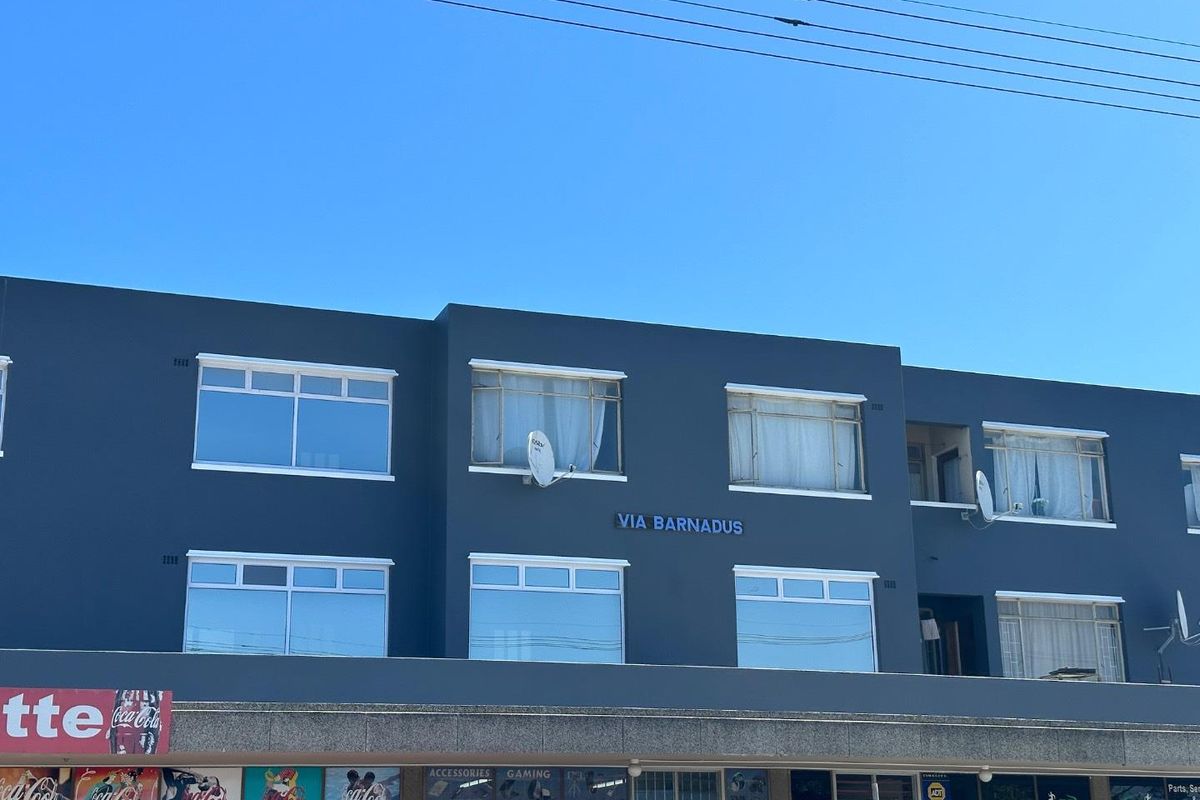 Front elevation of the Via Barnadus building featuring retail storefronts on the ground level and residential apartment windows above.