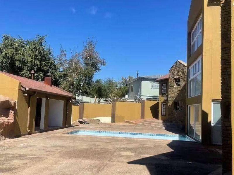 Outdoor pool area featuring a swimming pool, concrete patio space, and surrounding boundary walls with multi-story building access.