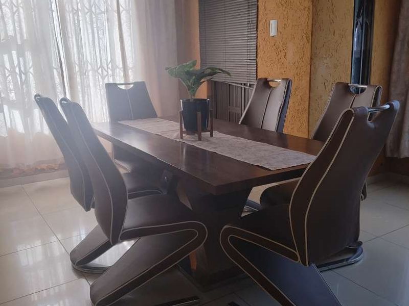 A dining room featuring tiled flooring, textured wall finishes, and a chandelier, providing a functional space for family meals.