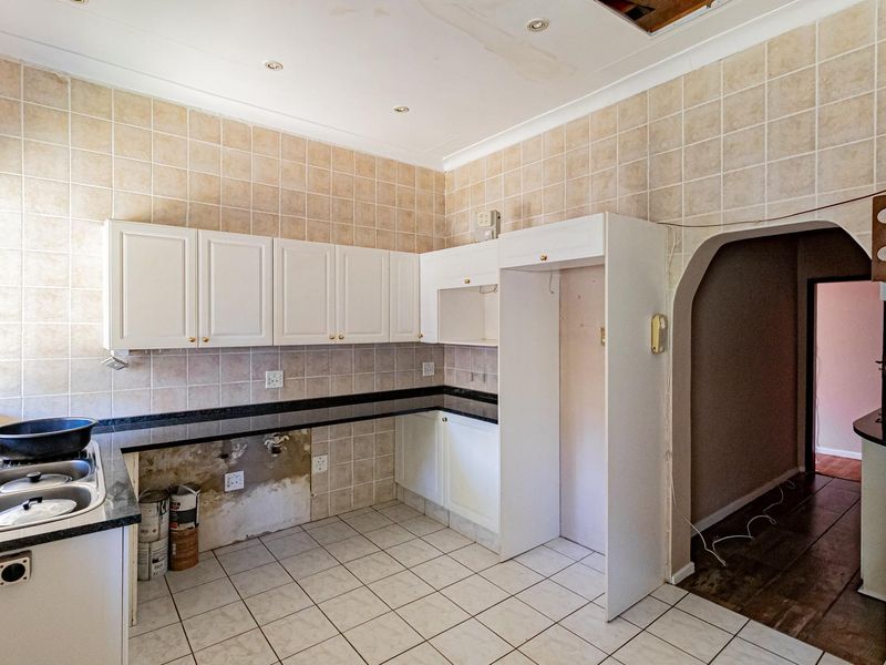 A kitchen space featuring built-in cabinetry and granite countertops, currently requiring repairs to the ceiling, wall finishes, and cabinetry components.