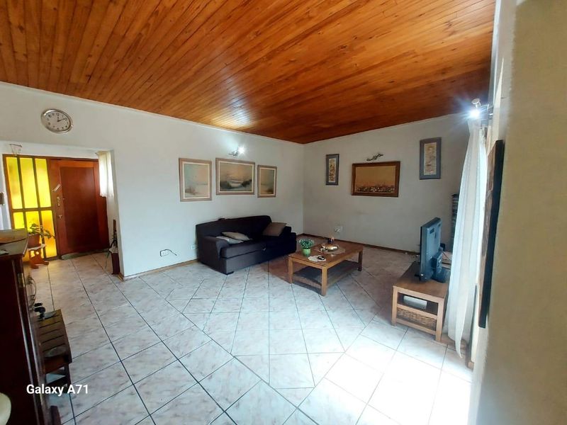 Spacious living room featuring ceramic floor tiles and a warm timber tongue and groove ceiling.