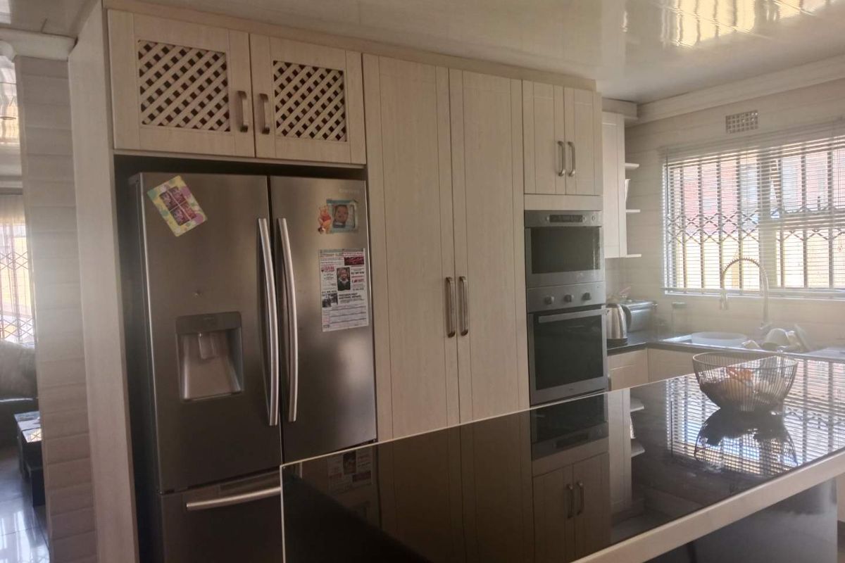 Modern kitchen featuring light wood cabinetry, built-in oven and microwave, and a sleek black countertop island, providing a functional and contemporary cooking space.