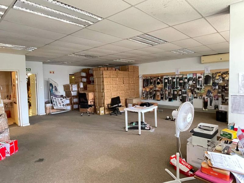 Open-plan office or commercial space featuring suspended ceilings, recessed lighting, and wall-mounted air conditioning, currently utilized for storage and administrative purposes.