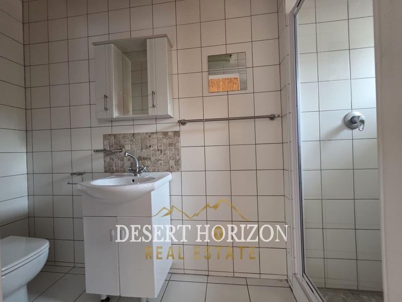 A functional bathroom featuring a pedestal vanity, wall-mounted medicine cabinet, and a separate shower enclosure with tiled finishes throughout.