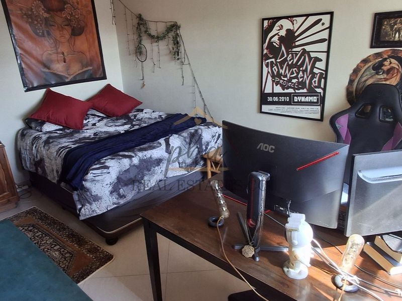 A bedroom featuring tiled flooring, currently utilized as a combined sleeping and workspace area.