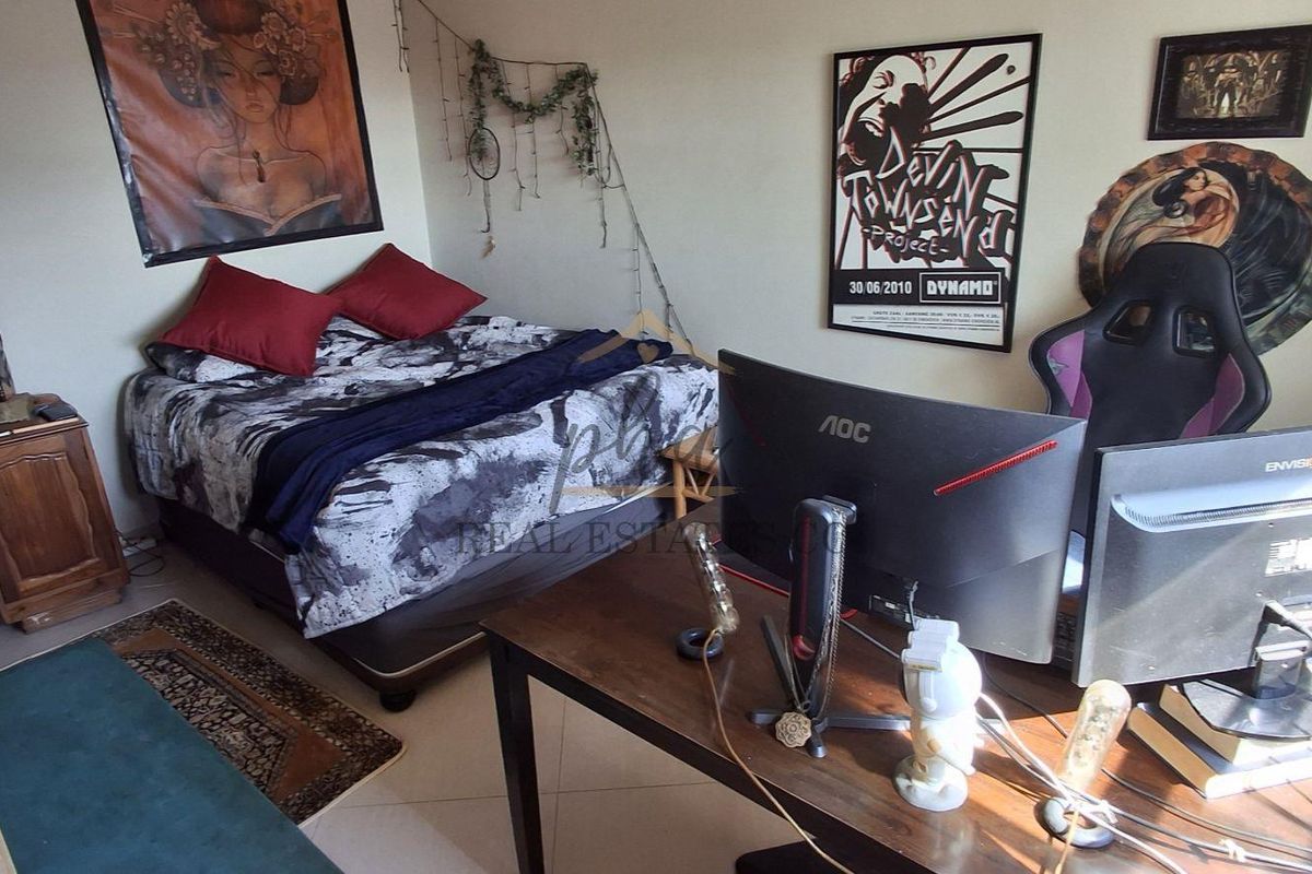 A bedroom featuring tiled flooring, currently utilized as a combined sleeping and workspace area.