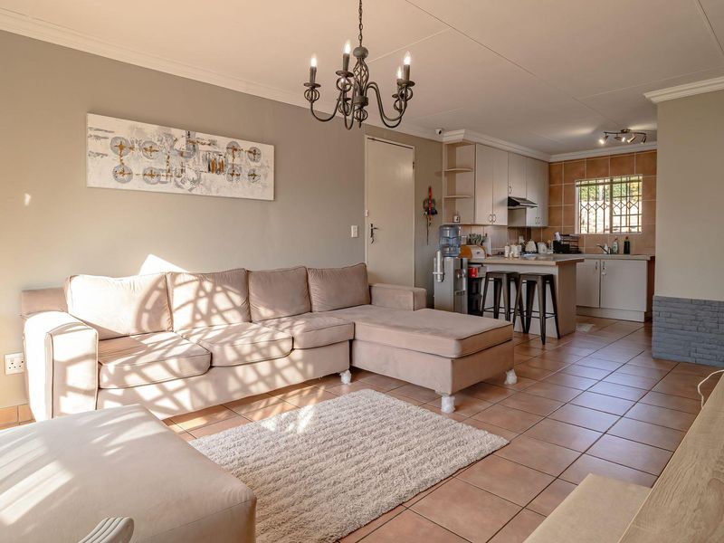 Open-plan living area featuring tiled floors, a functional kitchen with cabinetry and island, and a bright, connected layout suitable for modern living.