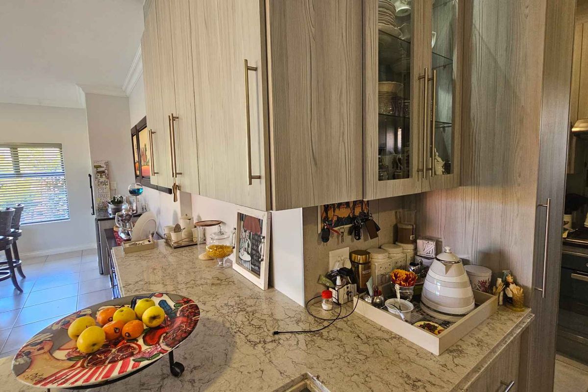 A functional kitchen area featuring light wood-grain cabinetry, stone-look countertops, and a built-in oven with an extractor fan.