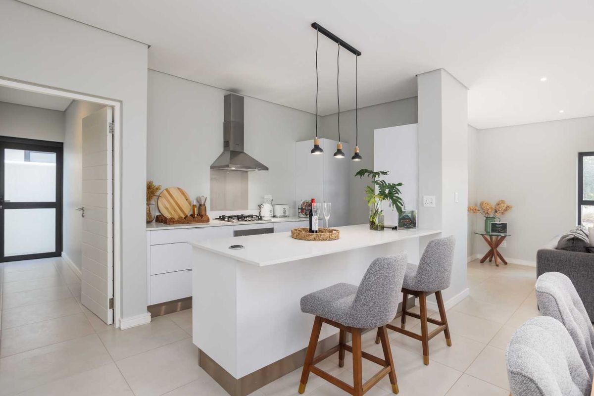 Modern kitchen featuring a central island with stone countertops, stainless steel appliances, and sleek cabinetry, seamlessly integrated into an open-plan living space.