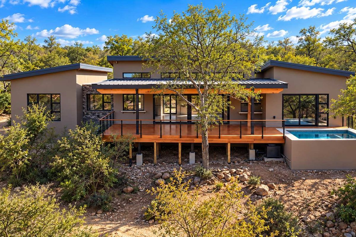Modern rear elevation featuring a spacious raised wooden deck, integrated plunge pool, and contemporary architectural design set against a natural landscape.