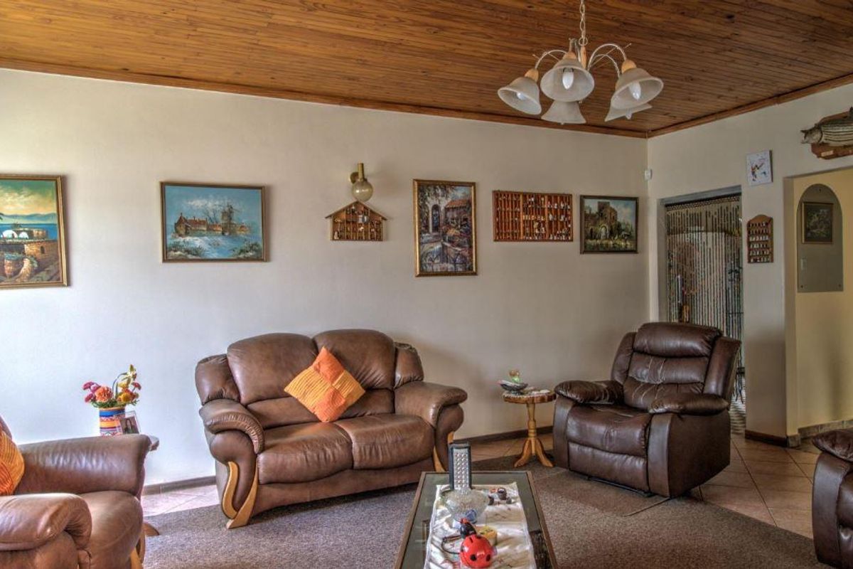 A living room featuring a timber-clad ceiling, tiled flooring, and a central ceiling light fixture.