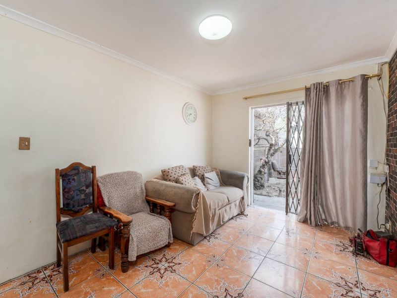 A living room featuring tiled flooring, a brick accent wall, and a sliding glass door providing access to the outdoor area.