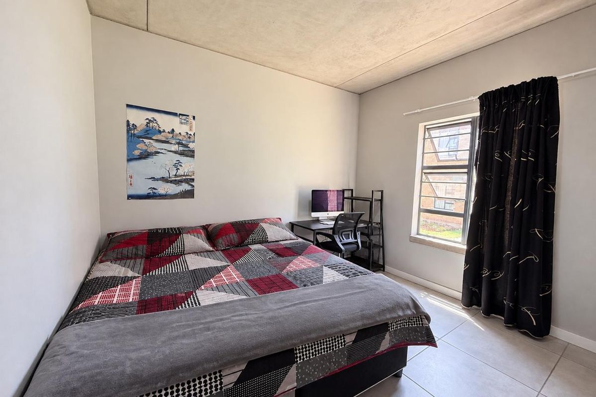 A bedroom featuring tiled flooring and an exposed concrete ceiling, providing a neutral base for interior design.