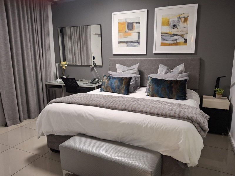 A well-maintained bedroom featuring neutral tiled flooring and modern grey wall finishes, creating a comfortable and contemporary living space.