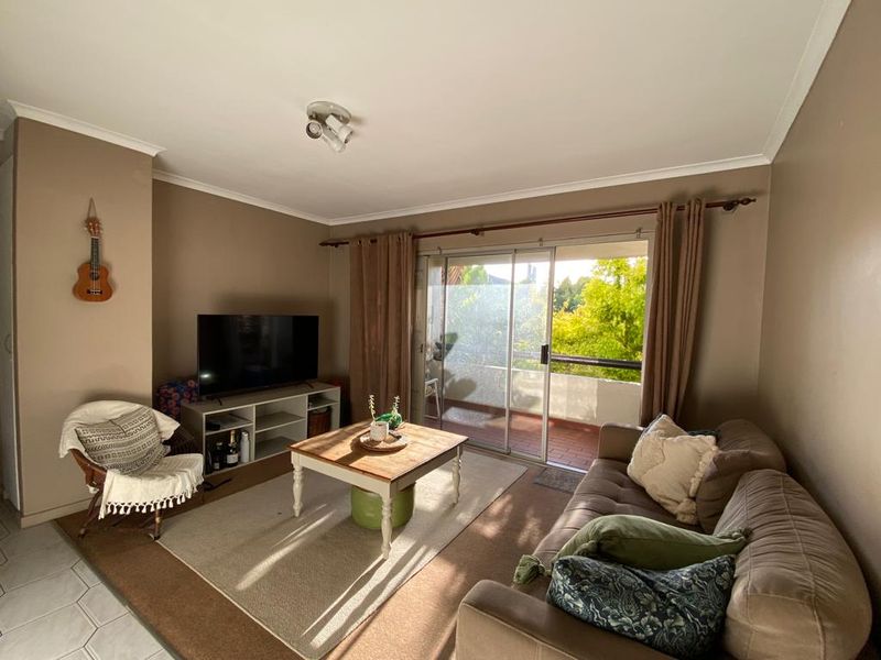 A comfortable living room featuring tiled flooring and a large sliding glass door that provides access to an outdoor balcony area.