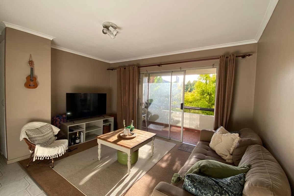 A comfortable living room featuring tiled flooring and a large sliding glass door that provides access to an outdoor balcony area.