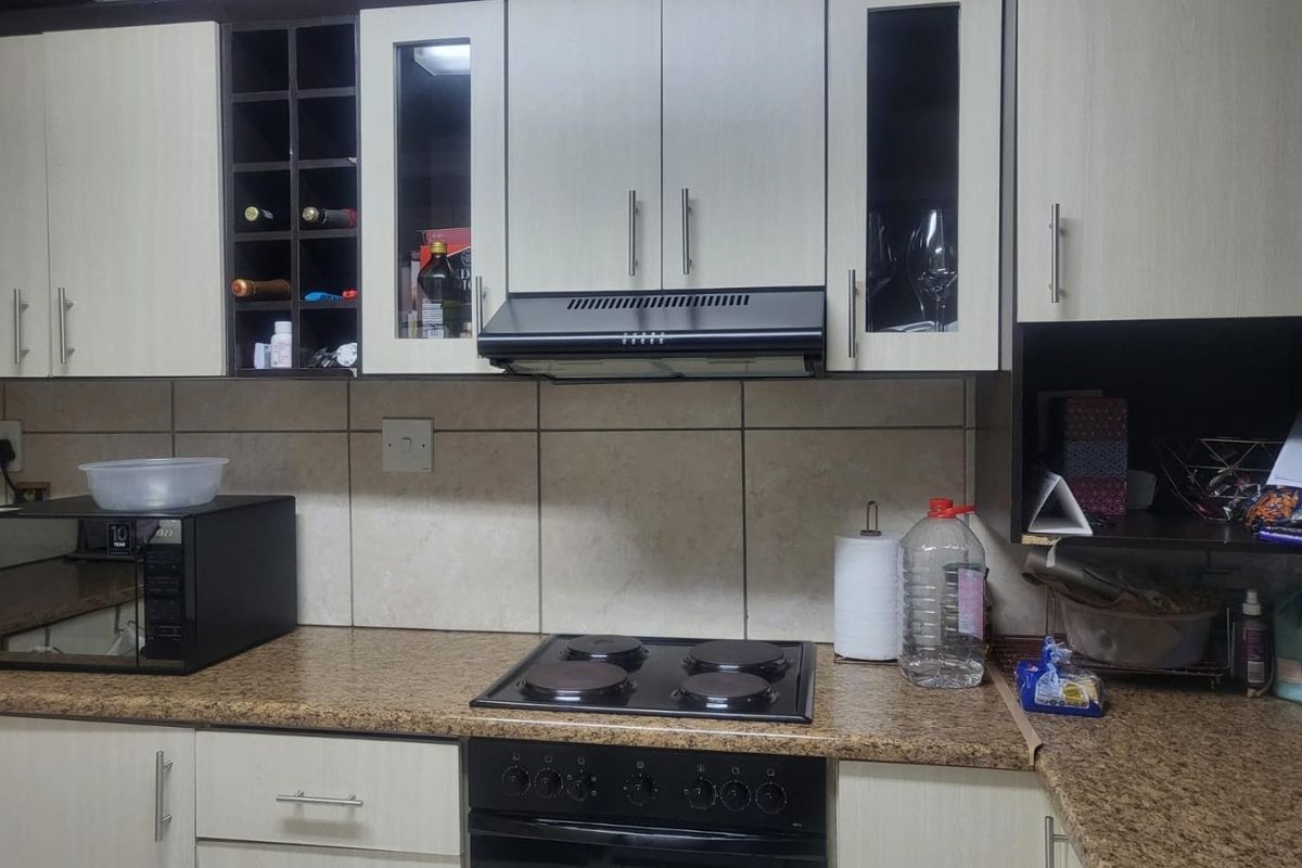 A functional kitchen featuring built-in cabinetry, a tiled backsplash, and integrated cooking appliances including an electric hob, oven, and extractor fan.
