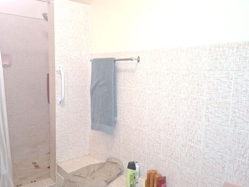 A functional bathroom featuring a shower enclosure with a grab rail and tiled wall finishes.