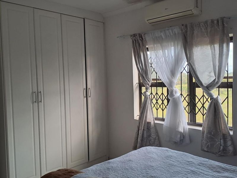 Bedroom featuring built-in cupboards, a split-system air conditioner, and security burglar bars on the window.