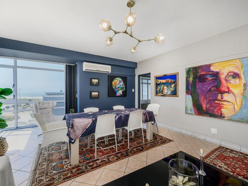 A bright dining area featuring tiled floors, a modern chandelier, and large glass sliding doors offering expansive views.