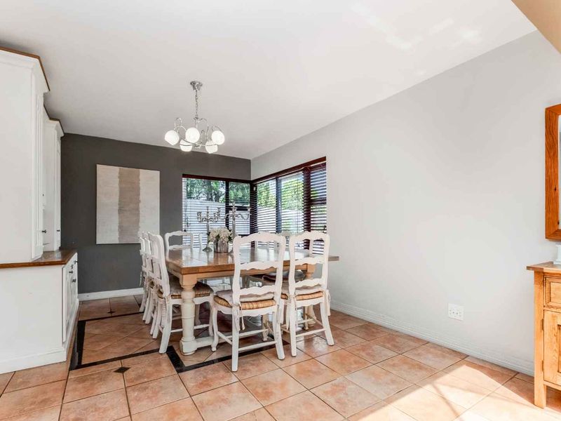 A bright dining room featuring tiled flooring, built-in cabinetry, and a classic chandelier, offering a functional space for family meals and entertaining.