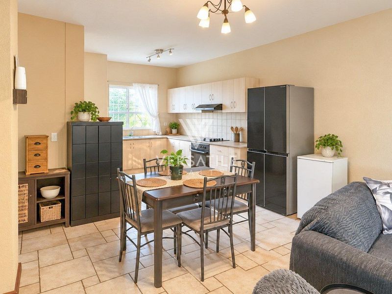 Open-plan kitchen and dining area featuring light wood cabinetry, tiled flooring, and integrated cooking appliances, creating a functional and connected living space.