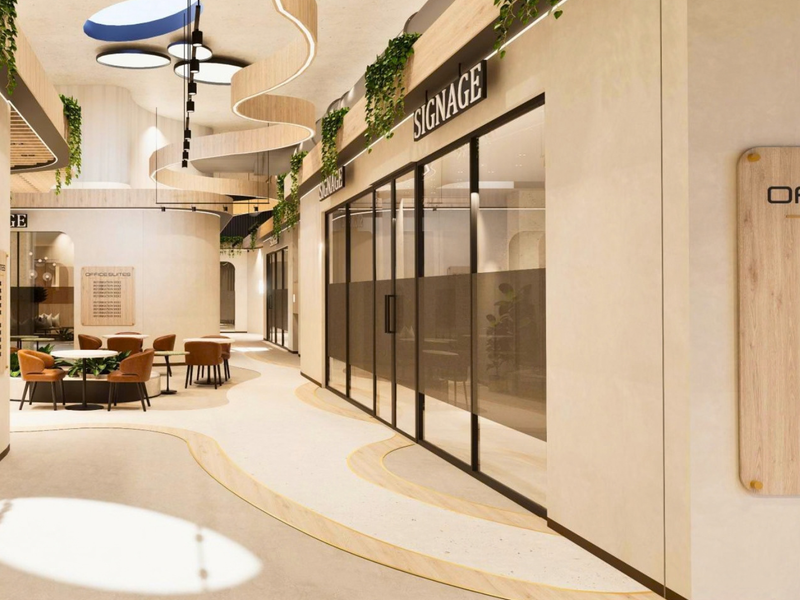 Modern office building hallway featuring curved architectural ceiling details, glass-partitioned office suites, integrated signage, and high-end terrazzo flooring.