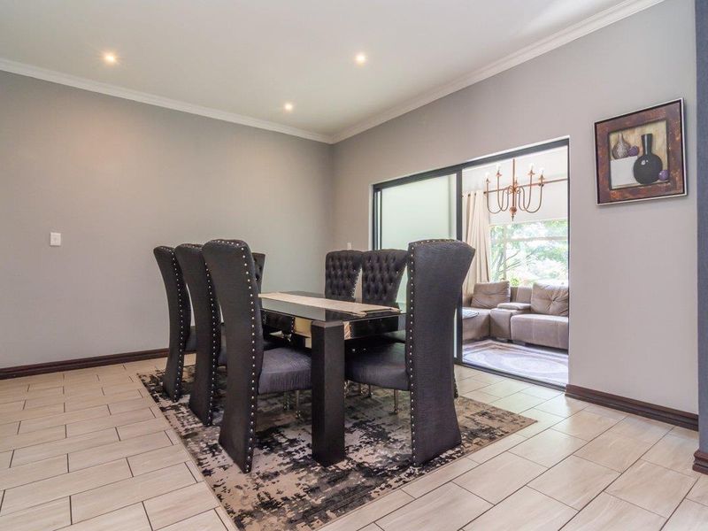 A well-maintained dining room featuring tiled flooring, recessed downlighting, and a sliding glass door providing access to an adjacent patio area.