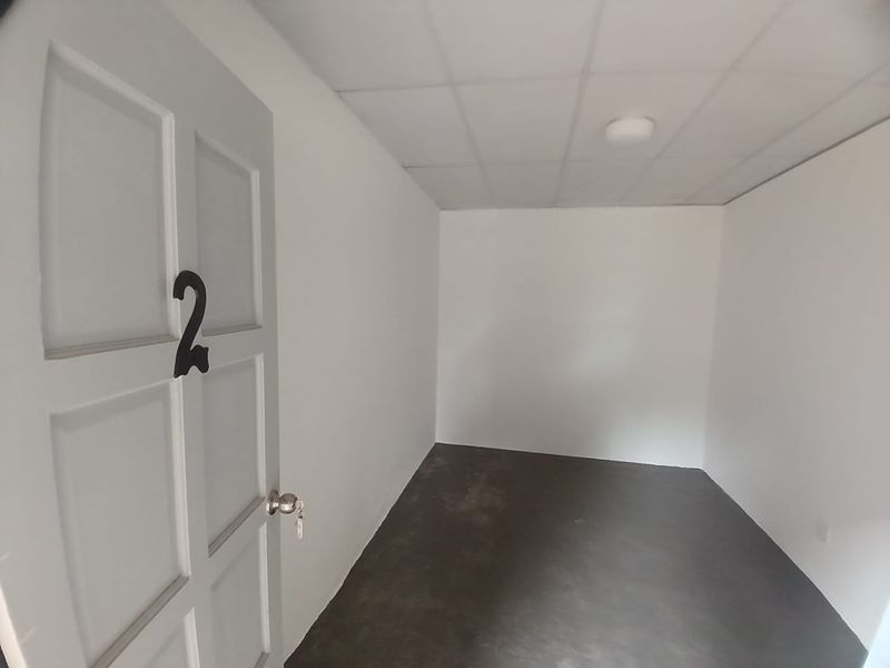 An empty, basic bedroom featuring a drop ceiling, flush mount lighting, and a numbered panel door, ready for renovation or staging.