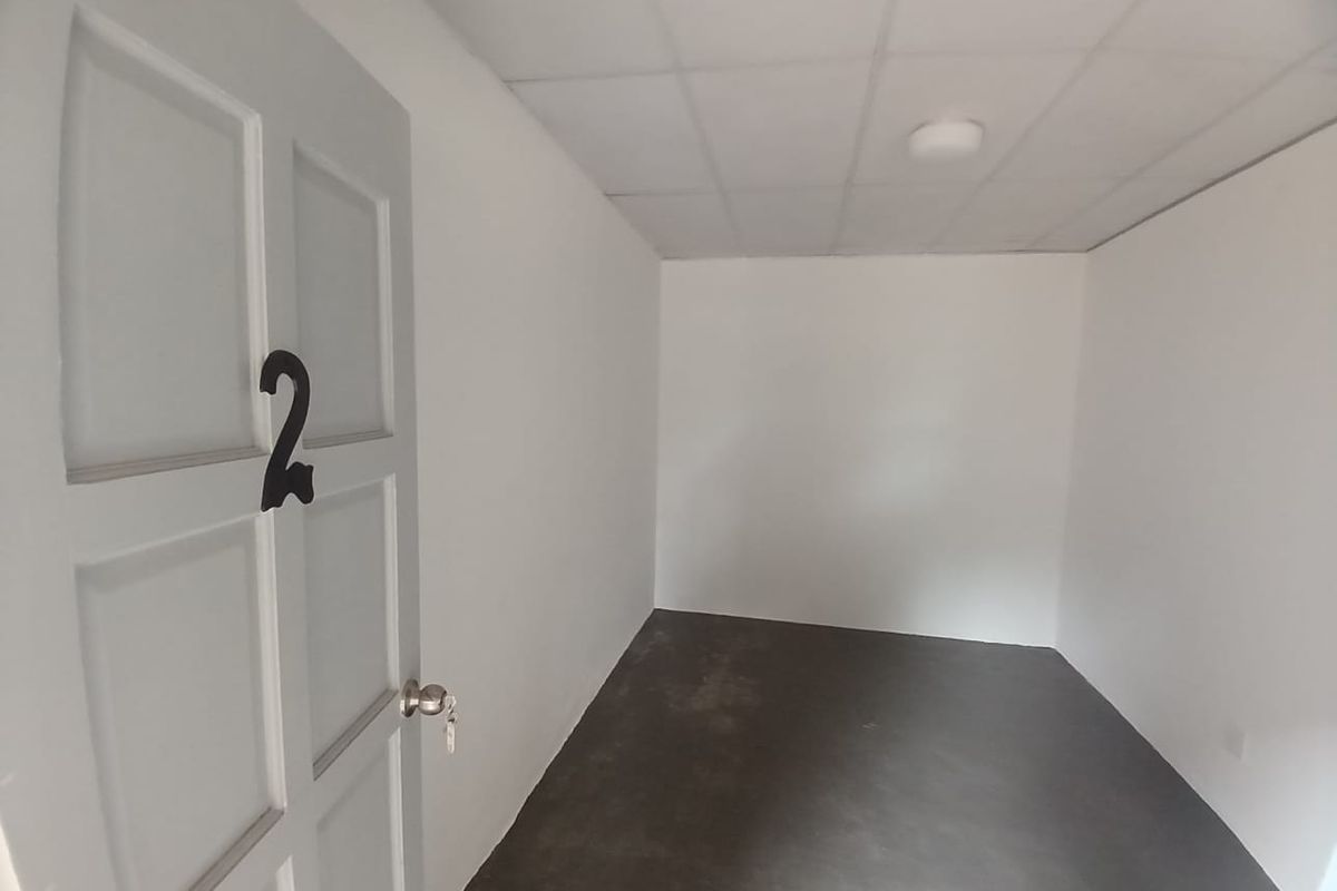 An empty, basic bedroom featuring a drop ceiling, flush mount lighting, and a numbered panel door, ready for renovation or staging.