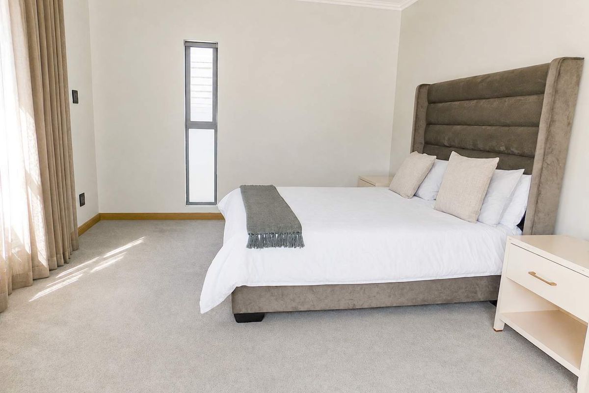A well-maintained bedroom featuring neutral carpeting, clean wall finishes, and a vertical window allowing natural light.