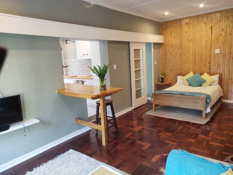 Open-plan living area featuring warm timber wall paneling, classic parquet flooring, and a convenient breakfast bar connecting to the kitchen space.