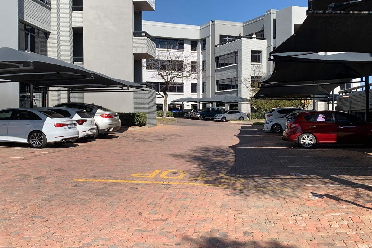 Exterior view of the office building complex featuring paved parking areas with shade cloth carports.