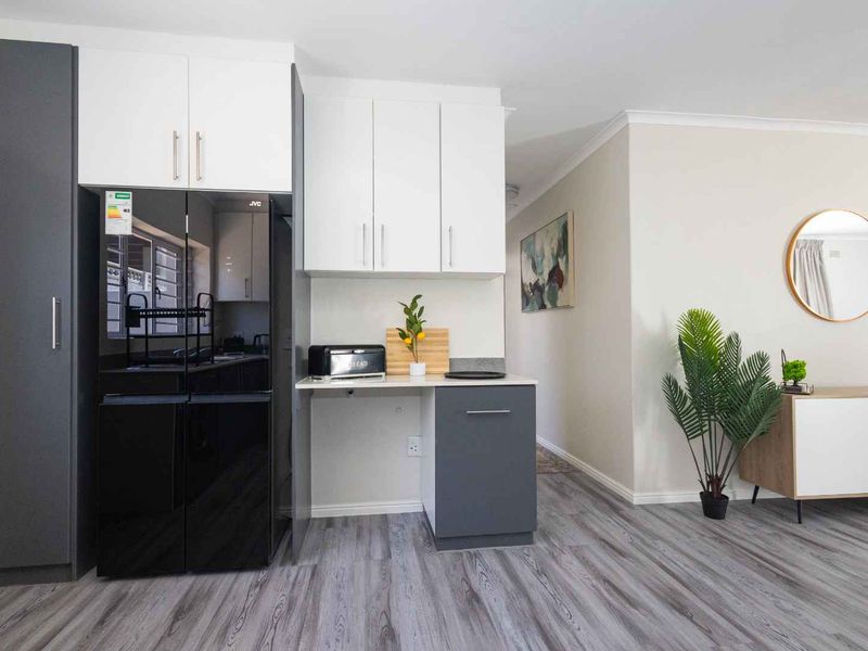 A modern kitchen area featuring sleek two-tone cabinetry, ample storage, and durable laminate flooring, seamlessly integrated into the open-plan living space.