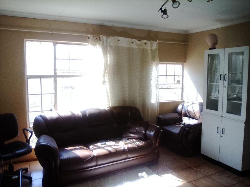 A living room featuring tiled flooring and multi-pane windows, requiring cosmetic updates to the walls and ceiling to improve the overall aesthetic.