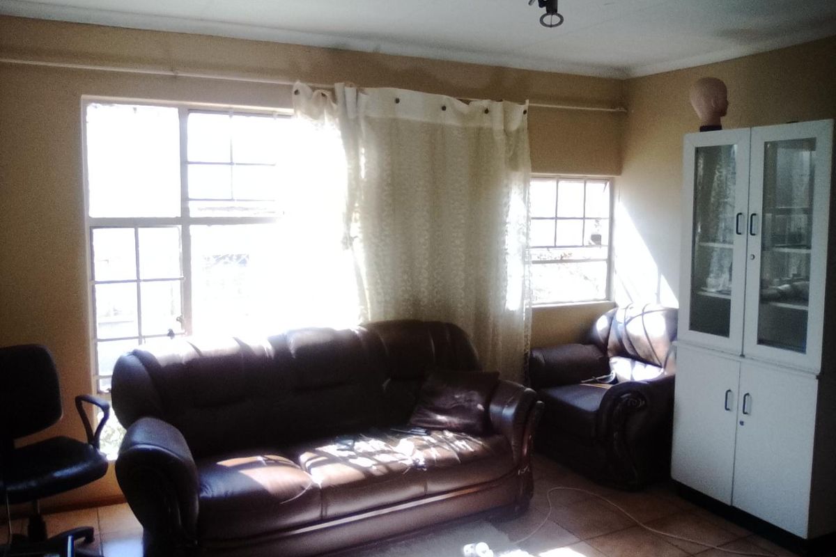 A living room featuring tiled flooring and multi-pane windows, requiring cosmetic updates to the walls and ceiling to improve the overall aesthetic.