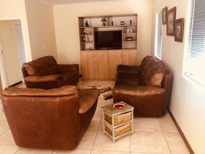 A living room featuring tiled flooring, built-in cabinetry, and venetian blinds, offering a functional space with potential for modern updates.