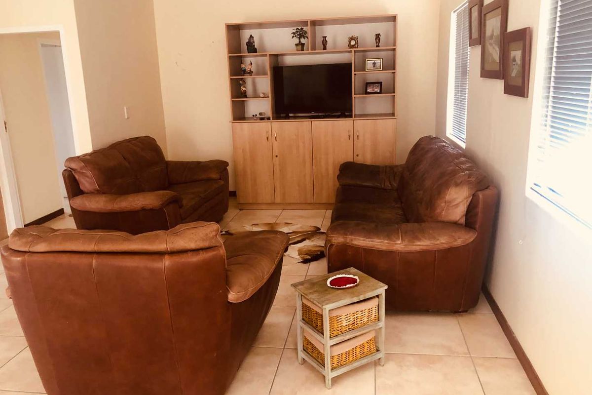 A living room featuring tiled flooring, built-in cabinetry, and venetian blinds, offering a functional space with potential for modern updates.