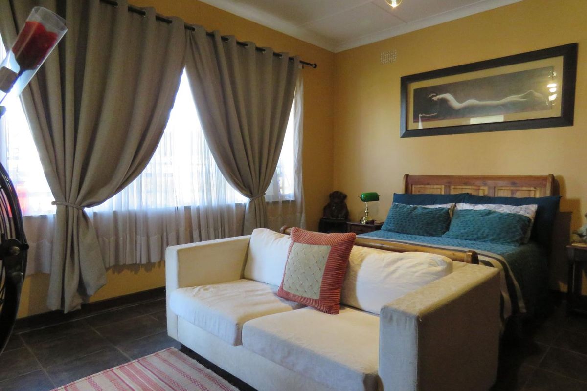 A bedroom featuring tiled flooring, neutral wall paint, and large windows with curtain fixtures.