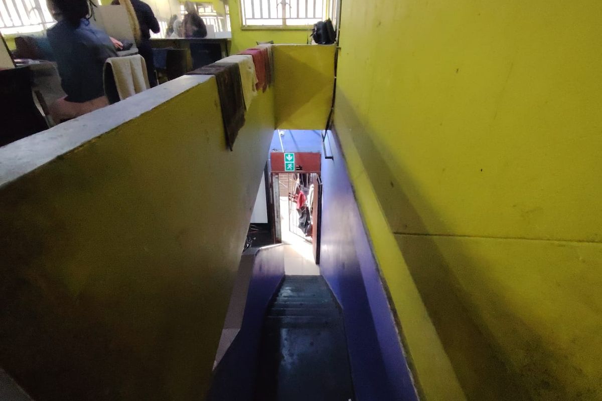 Interior staircase area connecting levels, featuring painted walls and a security gate at the exit.