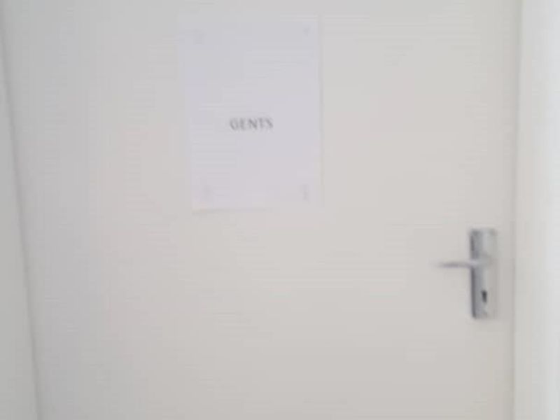 A plain white door leading to a gents restroom facility.