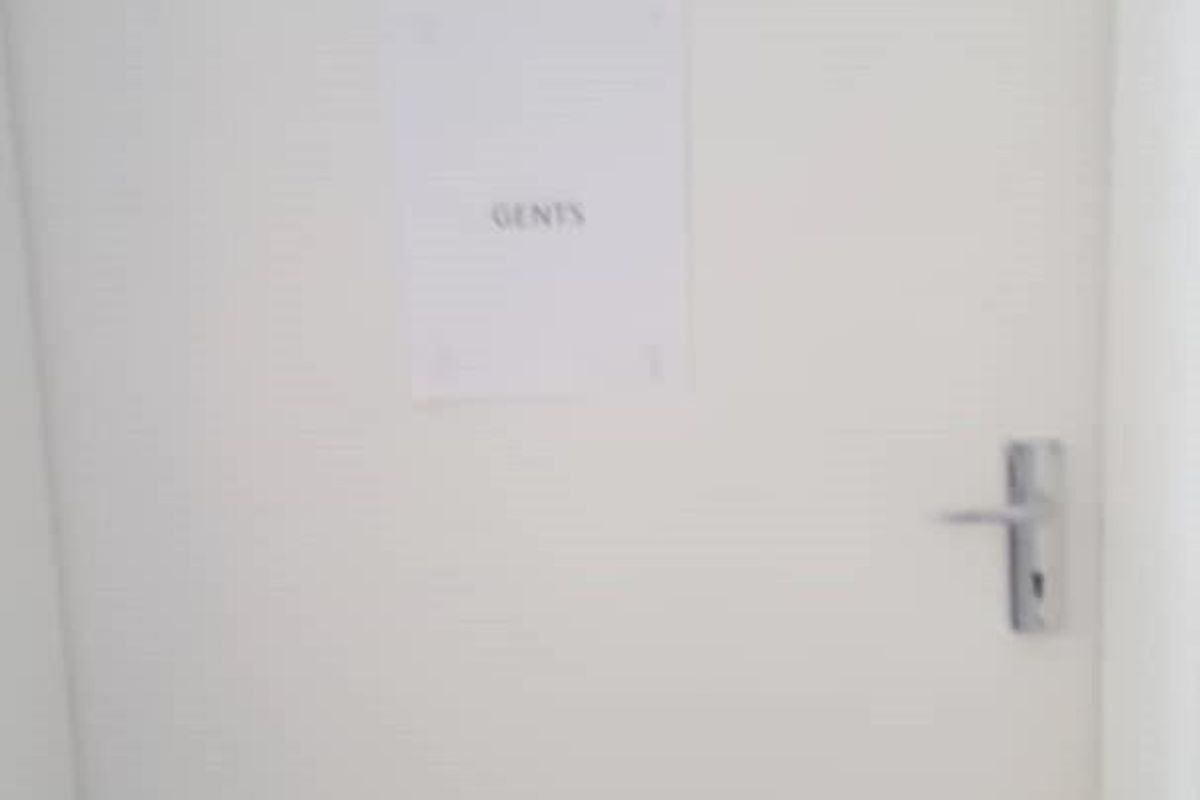 A plain white door leading to a gents restroom facility.